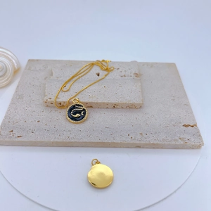 Macro detail of gold-plated celestial necklace with black enamel snake and moon pendants