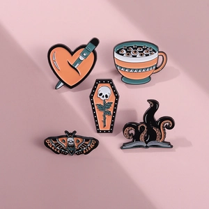 Detailed flat lay of gothic enamel pins featuring heart daggers and skull moth designs