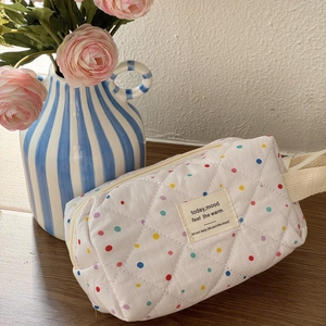 Macro detail of quilted white cosmetic bag with colorful polka dots and a fabric label