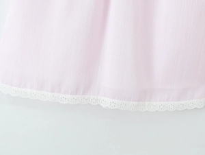 Close-up of pink and white striped woven fabric with delicate white lace embroidery detail