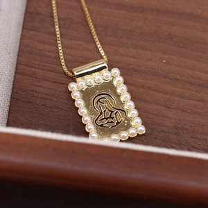Macro detail of gold religious pendant with hollow design and white pearl borders