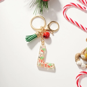 Close-up of Christmas resin letter L keychain with green tassel and red bell charms