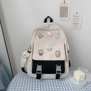 Detail of cream and black canvas student backpack with cute bear pendant and patches