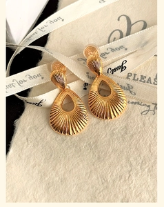 Gros plan de boucles d'oreilles clips dorées en forme de goutte sur un ruban de soie élégant