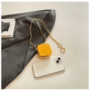 Close-up of mini yellow heart-style chain bag showing compact size and gold strap