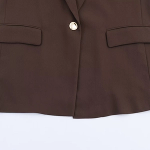 Detailed view of women's brown blazer featuring a gold button and flap pockets texture
