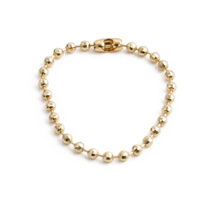 Bracelet minimaliste en perles dorées avec fermoir tonneau sur fond blanc pur