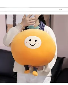 Close-up of cute round orange fruit plush pillow with smiling face held by model