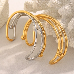 Détails de bracelets croisés dorés et argentés sur corail blanc et décor de plage