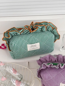 Close-up of quilted gingham storage bag featuring green checks and orange ruffle trim