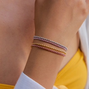 Gros plan de bracelets plaqués or 18 carats avec zircons roses sur un poignet de femme