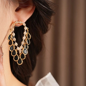 Macro shot of gold tassel earrings with clear cubic zirconia and black teardrop gems