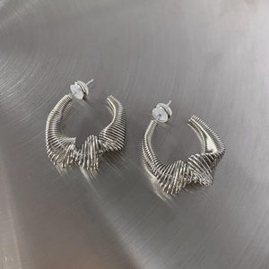 Macro shot of silver metal wire-wrapped U-shaped earrings on a brushed metal background