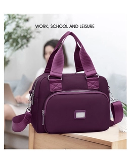 Macro shot of purple nylon shoulder bag with three-tier zipper and metallic logo plate