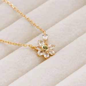 Detail of flower necklace with white petals and green zircon stone in 14K gold finish