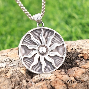 Detailed view of silver sun totem pendant on rustic bark texture with 29g weight