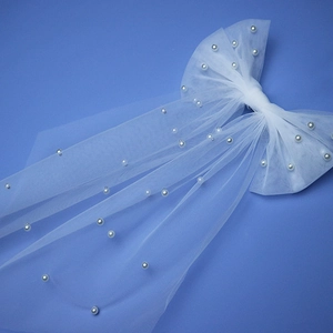 Close-up of white mesh bow hair clip with faux pearls for bridal photography accessories