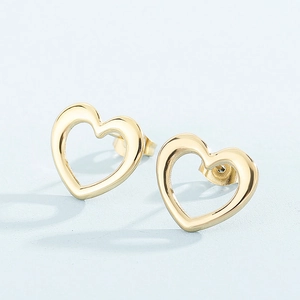 Detailed view of gold-toned heart-shaped stud earrings on a soft blue background