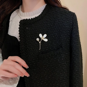 Détail d'une élégante broche fleur dorée avec perles et zircon sur une veste en tweed