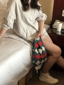 Close-up of knit tote bag with red, green, and white diamond pattern in casual lifestyle setting