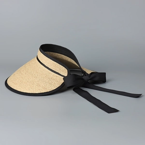 Detail of raffia sun hat featuring woven straw texture and long black silk bow tie