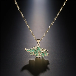Detailed macro shot of a gold-plated triceratops pendant set with green cubic zirconia