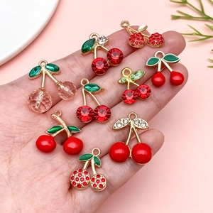 Handheld view of sweet cherry pendants with red rhinestones and gold alloy for DIY jewelry