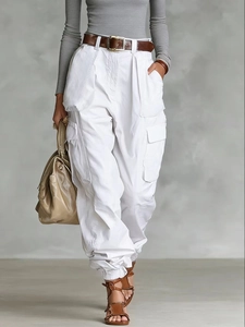 Detail view of white high-waisted cargo pants with pockets and a brown leather belt