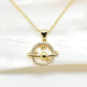 Macro detail of 18k gold-plated planet pendant with sparkling white cubic zirconia
