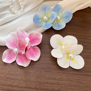 Close-up of summer style fabric flower hair clips with pearls on elegant wood surface