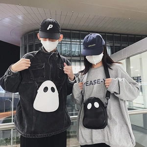 Street style shot of quirky ghost-shaped PU crossbody bags in black and white colors