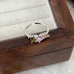 Close-up of silver ring featuring multi-colored zircon stones in a wooden jewelry box