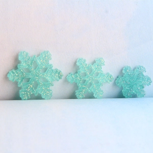 Close-up of blue resin glitter snowflakes in three sizes for DIY craft decorations