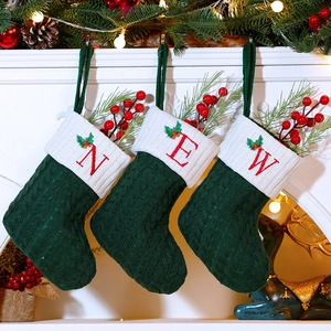 Close-up of three knitted Christmas stockings with NEW embroidery hanging on a fireplace
