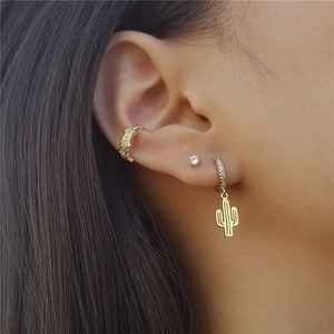 Detailed view of gold cactus hoop earring, star cuff, and single diamond stud set