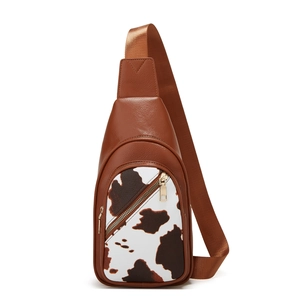 Close-up of cow pattern patch and golden zipper on brown leather crossbody bag