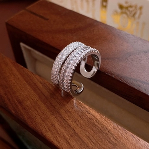 Makroaufnahme eines silbernen Doppelrings mit funkelnden Zirkonia auf einer Holzbox
