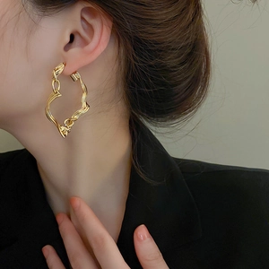 Minimalist gold twisted geometric hoop earrings in irregular liquid metal style