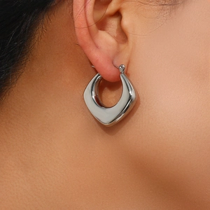 Detailed view of silver hoop earrings featuring a polished diamond-cut faceted surface
