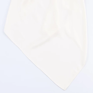 Vue détaillée de la texture du tissu en mousseline blanche et de l'ourlet asymétrique