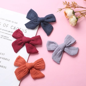 Detail showing four assorted colors of cotton bow headbands for babies on pink background