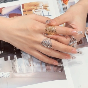 Three hollow rose and crown rings in gold and silver finish worn on a model's hand