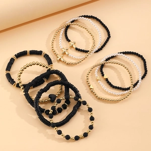 Dettaglio di bracciali elastici boho con croce dorata, cuore e perline miste