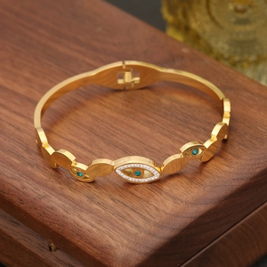 Detailed close-up of golden evil eye bangle with turquoise stone and white zircons