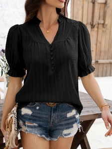 Detail of black V-neck top with textured fabric, button decor, and flared ruffle sleeves