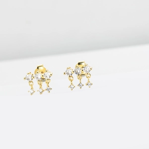 Detail of gold tassel stud earrings featuring three clear cubic zirconia stones