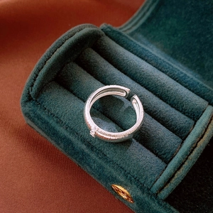 Macro detail of brushed silver ring with small zircon in green velvet jewelry box