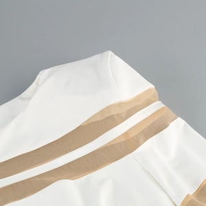 Detail shot of white dress featuring brown mesh patchwork and precision stitching finish