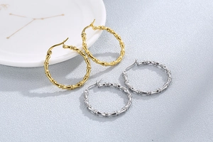 Makroaufnahme von Bambus-Ohrringen in Gold und Silber auf einem Keramiktablett