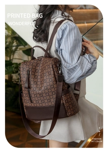 Detail view of stylish vintage brown printed backpack worn by model in a soft indoor setting